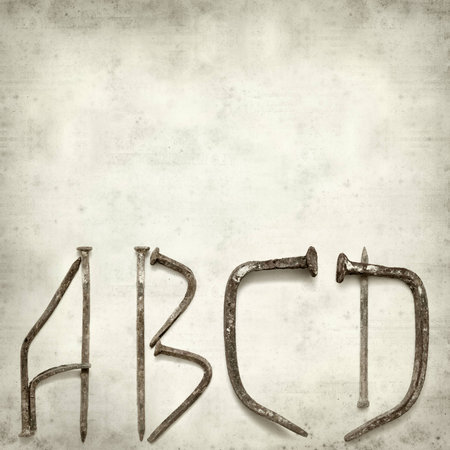 textured old paper background with forged nail letters partial alphabetの写真素材