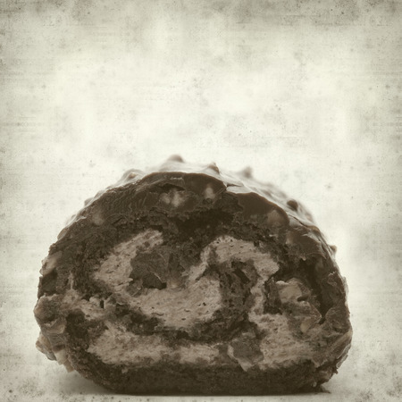 textured old paper background with chocolate roll cakeの写真素材