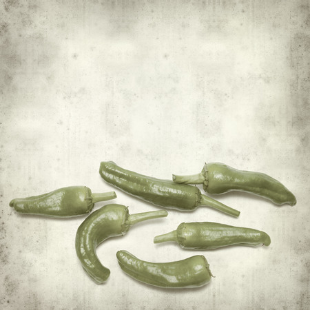 textured old paper background with green padron peppersの写真素材
