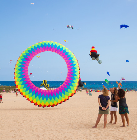 FUERTEVENTURA, SPAIN - NOVEMBER 08: Viewers watch from the ground as multicolored kites fill the sky at 27th International Kite Festival, November 08, 2014 in Dunes of Corralejo, Fuerteventura, Spainのeditorial素材