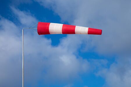windsock indicating strong wind on blue sky with light clouds background