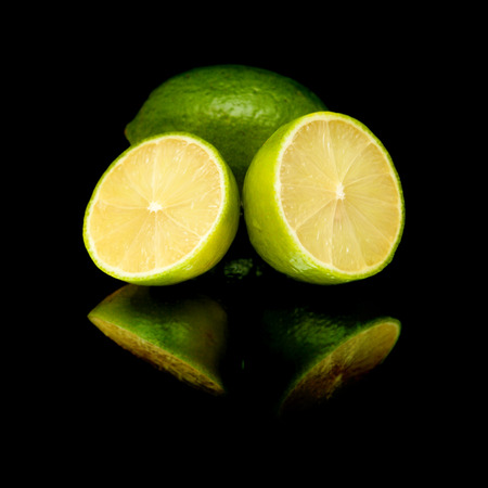 lime fruit on black mirror, isolatedの写真素材