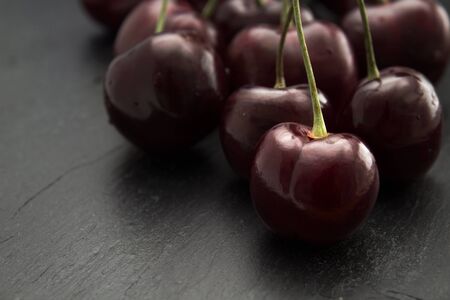dark red cherries on a black slate surfaceの写真素材