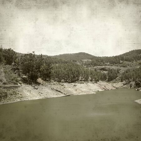 textured old paper background with canarian pine trees and reservoirの写真素材