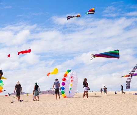 FUERTEVENTURA - NOVEMBER 13: Viewers watch from the ground as multicolored kites fill the sky at 24th International Kite Festival (Festival de Cometas), November 13, 2011 in Dunes of Corralejo, Fuerteventura, Spainのeditorial素材