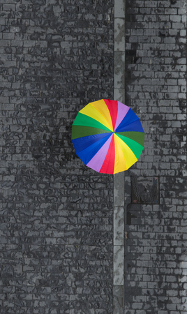 rainbow umbrella on wet pavement, shot from aboveの写真素材
