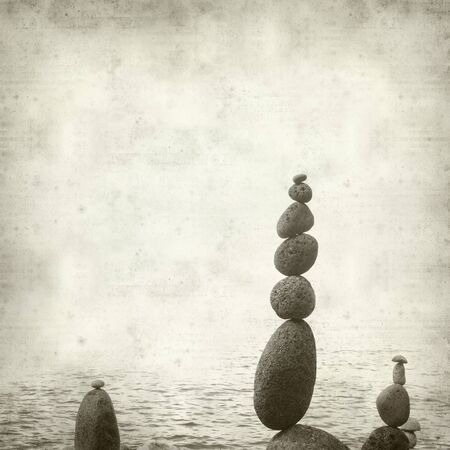 textured old paper background with pebble cairnsの写真素材