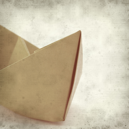 textured old paper background with origami paper boatの写真素材