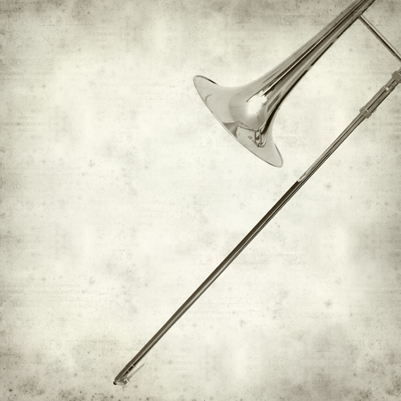textured old paper background with silver tromboneの写真素材