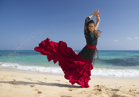 young attractive woman in red and green  flamenco dress by ocean shoreの写真素材