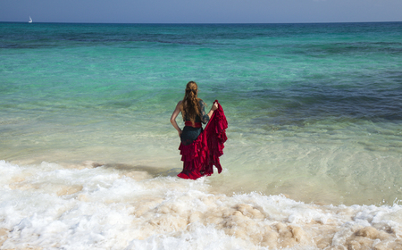 young attractive woman in red and green  flamenco dress by ocean shoreの写真素材