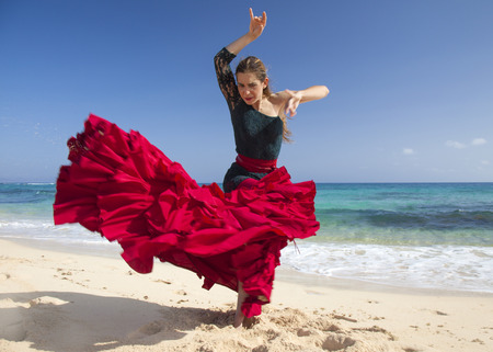 young attractive woman in red and green  flamenco dress by ocean shoreの写真素材