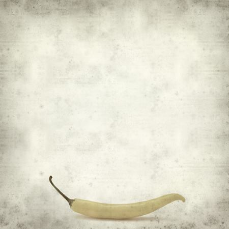 textured old paper background with yellow chilli pepperの写真素材