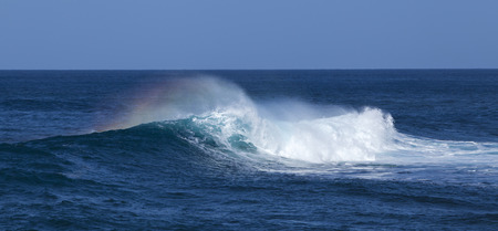 powerful ocean waves with rainbow plume breaking by the shores of Gran Canariaの写真素材