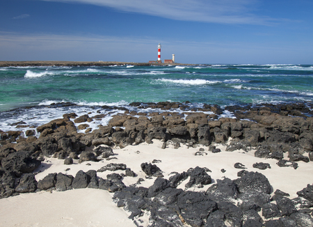 Fuerteventura, Canary Islands, newly painted Faro de Toston seen over white sand coves of Los Lagos...