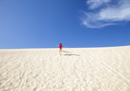 Fuerteventura sand dunes in the north of the island, teenage boy in red t-shirt and shorts running downの写真素材