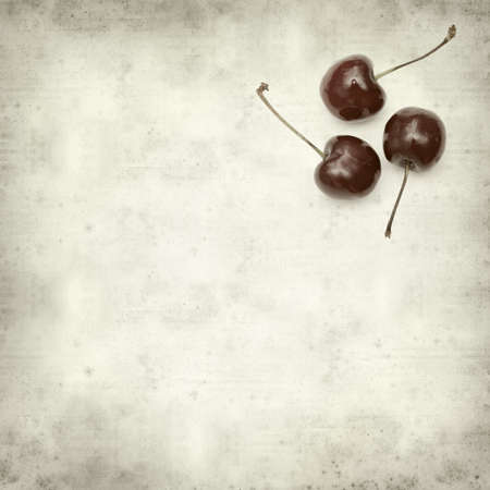 textured old paper background with dark red cherriesの写真素材