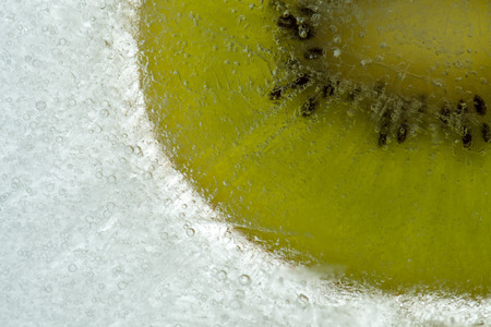 kiwi fruit frozen into a block of iceの写真素材