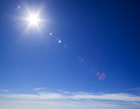 natural sky background with star-shaped sun and light clouds at the bottom, flareの写真素材