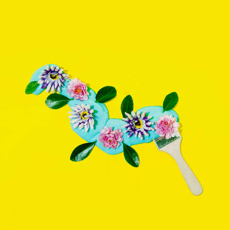 Painting brush with blue slime and colorful flowers. Spring composition on a yellow background.の写真素材