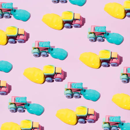 Pastel trucks transporting slime in blue and yellow. Pastel pink background.の写真素材