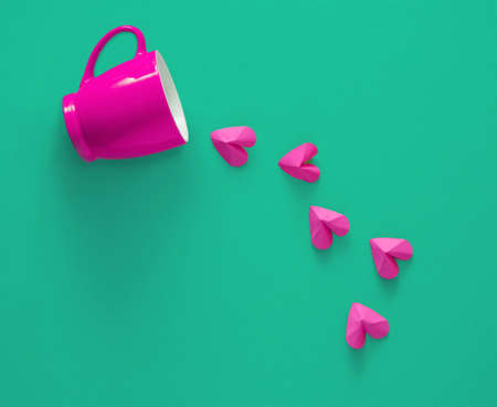 a cup that spills pink hearts on a green background
