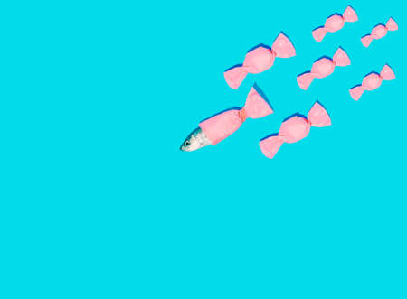 Fish in a candy bag on a blue background. Minimal composition. Copy space.の写真素材