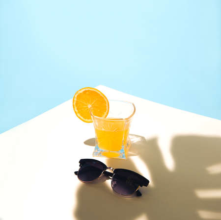 Summer tropical composition with yellow orange juice and sunglasses with monster leaf shade.の写真素材
