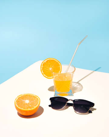 Summer composition with yellow orange juice on the table with sunglasses. Sunny summer day.の写真素材