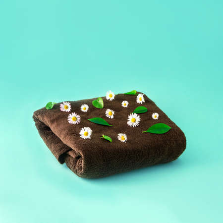 Brown blanket with white spring flowers and green leaves. Blue background.
