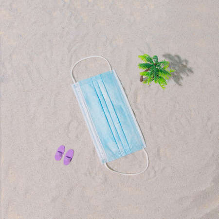 Summer scene with sand. A beach towel as a mask for a pandemic. Enjoying the sea. Minimal...