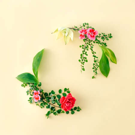 A wreath of flowers with leaves as a frame. Place for text. Flowers on the table.