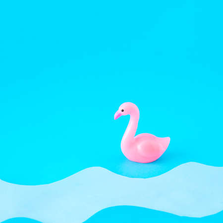 Pink flamingo on the beach with waves. Blue background.