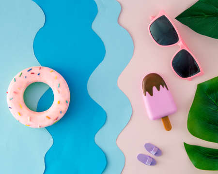 Summer scene with waves on the beach, with ice cream, sand, sunglasses and swimming tires.の写真素材