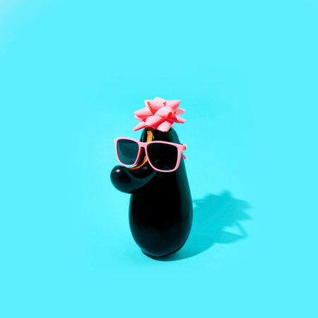 Eggplant with pink sunglasses and a pink bow. Minimal aesthetics on a blue background.の写真素材
