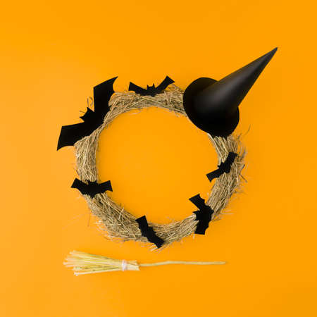 Creative look made of autumn tree branches with bats, a hat and a broom for witches. Minimum flat laying. Halloween concept. On a yellow background.の写真素材