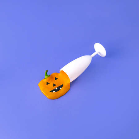 A white glass from which comes an orange scary pumpkin. On purpple backgrounds. Creative minimal...