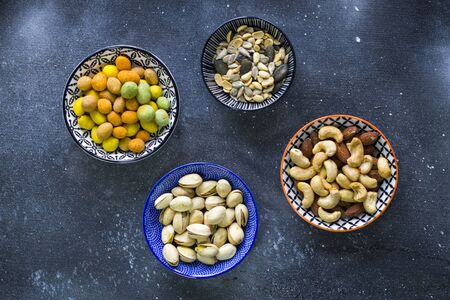 Nuts in bowls on the table, almonds, cashews and coasted nuts on the blue background. Colorful nuts...