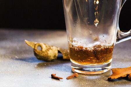 Grog in the tea glass, rum and warm tea with cinnamon on the black background.