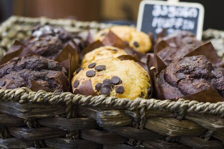 Large group of muffins in wooden bowl with chocolate and name letter. In cafe.の写真素材