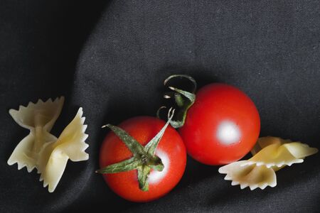 Spaghetti and farfale ingredient tomatoes and souse with spices on the black background, studio shoot.の写真素材