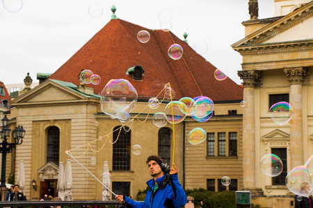 Soap bubbles in the street of Berlin, Germany. Man entertain people and tourist near the concert hall.のeditorial素材