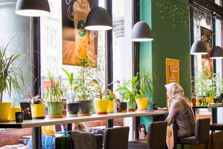 TBILISI, GEORGIA - MART 03, 2019: Young asian girl sitting in cafe and drink coffee, cafe interior in city center of Tbilisi.のeditorial素材