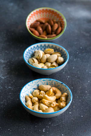 Nuts mix, beer snack on the bowl. Studio shoot. Cashews and coasted nuts on the blue background. Colorful nuts set.の写真素材