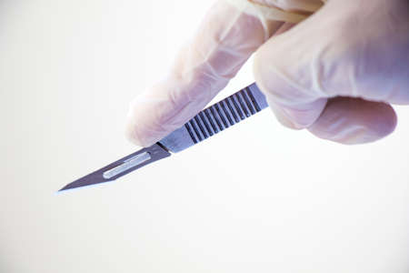 Surgery knife holding on the white background, studio shot. Operation equipment.の写真素材