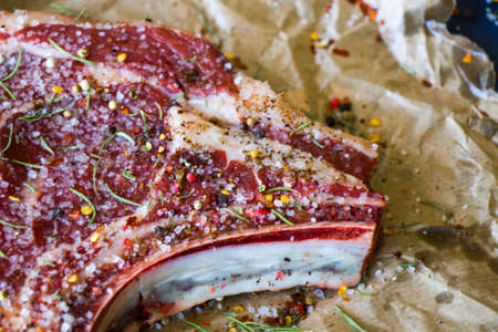 Raw beef meat on the table, spices and Rosemary, Rib eye steak ingredients. Pepper and coarse salt
