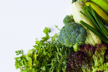 Green vegetable leaves on the white background, raw tarragon, zucchini, cabbage and cucumber