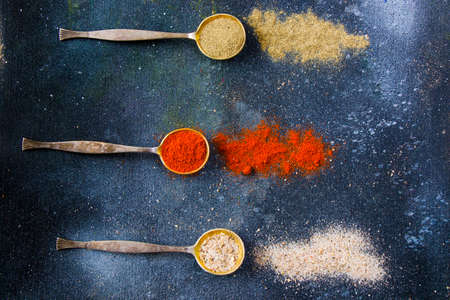 variation of spices on the vintage silver spoons, all spices on the table, colorful food background
