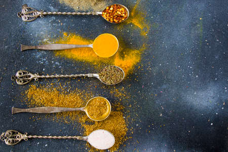 variation of spices on the vintage silver spoons, all spices on the table, colorful food background