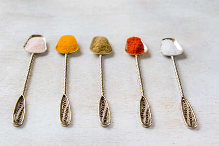 variation of spices on the vintage silver spoons, all spices on the table, colorful food backgroundの写真素材
